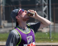 A runner drinks water with water droplets in the air