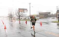 A man running on the street with pylons on the road
