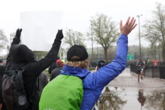 A pair are seen holding a sign and waving to runners