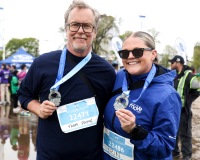 Two runners smile at the camera and hold their medals.
