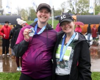 A pair of runners smile and hold up their medals