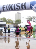 Runners are seen just about to cross the finish line with one runner in mid air