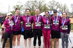 Runners in matching purple shirts  smile in a group photo