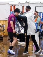 A runner has their medal put around their neck by a smiling volunteer.