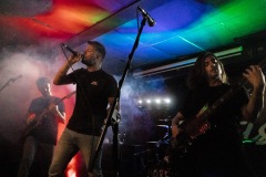 Musicians playing music amidst smoke and coloured lights