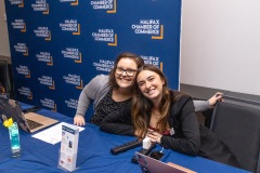 Two staff members smile to the camera at the check in table