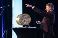 A man points to the crowd as they announce the winner of a raffle prize 