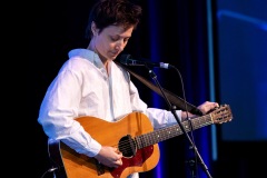 A person tunes their guitar on stage
