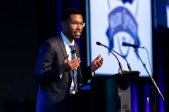 A man at the podium gestures while speaking to the crowd
