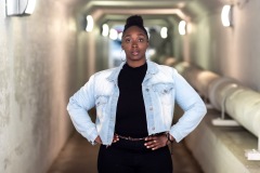 A woman poses and smiles by a tunnel with leading lines of lights