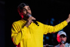 A man raises their arm while speaking on stage