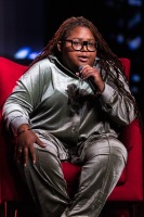 A person sits in a red chair speaking into the microphone