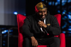 A man laughs while sitting on a red chair