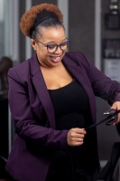 A woman smiles and laughs as she straightens hair.