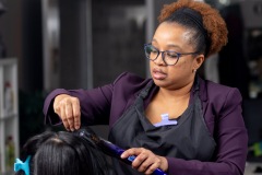 A woman  focuses on straightening hair.