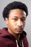 A man looks directly into the camera in front of a plain background.